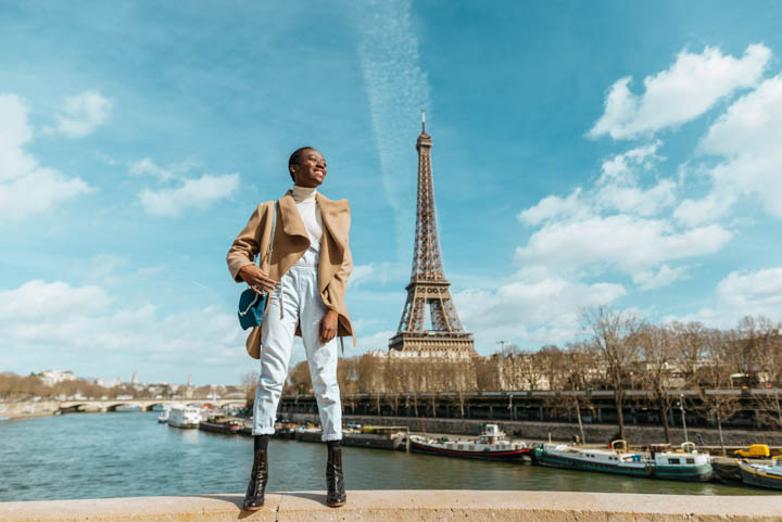 France, Paris, Smiling woman standing on a bridge with the Eiffel tower in the background