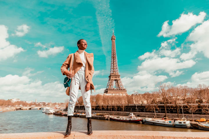 France, Paris, Smiling woman standing on a bridge with the Eiffel tower in the background